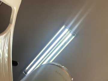 A close-up video of a shiny, cylindrical object with a bright light emitting from one end, casting a glare on a dark background, possibly a car's interior.