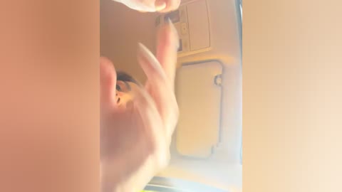 Video of a person's hand holding a cigarette, reflected in a mirror. The image is slightly blurred, with a warm, yellowish tint. The person's face is not visible, and the background shows a yellow door.