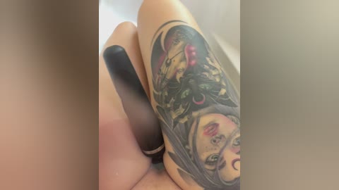 Video of a person's hand holding a black marker, with a large, colorful tattoo of a woman's face with flowers on the forearm.