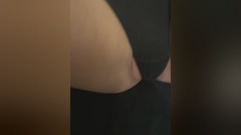 A video of a close-up of a person's bare buttocks and lower back, showing light skin tone, a black thong, and dimly lit surroundings.