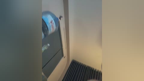 A video of a narrow, dimly lit stairwell with beige walls and a gray carpet runner, featuring a partially visible, blurred soda can on a window ledge.