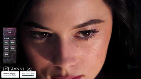 Close-up video of a woman with fair skin, dark hair, and light makeup. She has prominent eyebrows and long lashes. A smartphone screen shows TikTok video statistics.