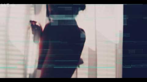 A blurred, silhouette image of a person with short hair, likely a woman, standing in front of a window with vertical blinds, displaying a digital screen overlay of text and numbers in green and white.