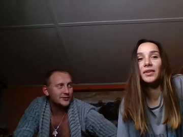 Video of a man with short hair and a woman with long, blonde hair, both smiling, indoors with dim lighting.