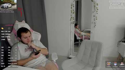 A video captures a man wearing a plush animal hat and pajamas, sitting on a white chair in a minimalist room with a mirror reflecting another person.