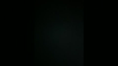 Video of a dark, indistinct figure in the center of a mostly black background, with a hint of light emanating from the figure's chest area, creating a vague silhouette.