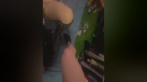 Video: A person in a green jacket kneels on a bed with blue sheets. A man, nude, is on his knees in front of her, with blurred faces.