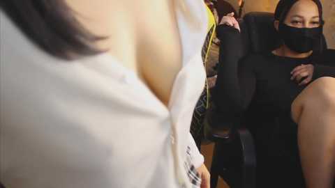 Video of a woman in a black mask and black top being restrained by a white-shirted person in a clinic.