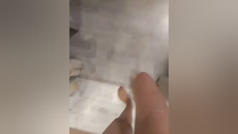 A close-up video of a hand holding a cigarette lighter, lighting a white sheet of paper on fire. The background shows a messy, cluttered room with a beige carpet and various scattered objects.