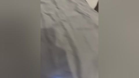 A blurred video of a person's legs and torso in a bed, covered in white sheets, with a soft, dimly lit room in the background.