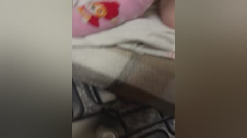 A close-up video of a person's thigh and foot, wearing a pink sock with a cartoon character, on a gray carpet.