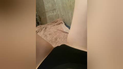 Video of a person sitting in a bathtub with light skin, wearing black panties, and a pink towel on the tiled wall.