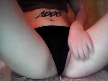 Video of a light-skinned person with a tattoo of \"love\" on their lower abdomen, wearing black panties, seated on a carpeted floor.