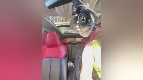 Video of a driver's view inside a car with red and black seats, wearing a high-visibility vest, and a camera attached to the dashboard.
