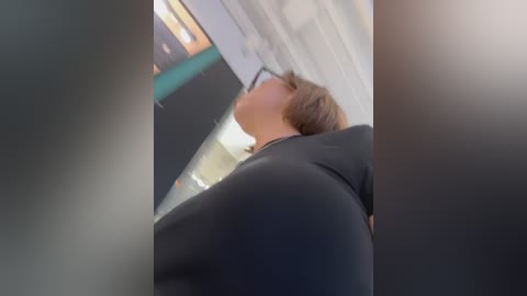 Video of a person in a black suit, viewed from below, with blurred background. The person appears to be looking upwards.