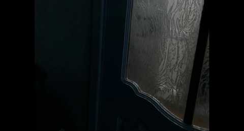 A video of a dimly lit, misty windowpane with intricate, etched designs. The background is dark, creating a moody, mysterious atmosphere.