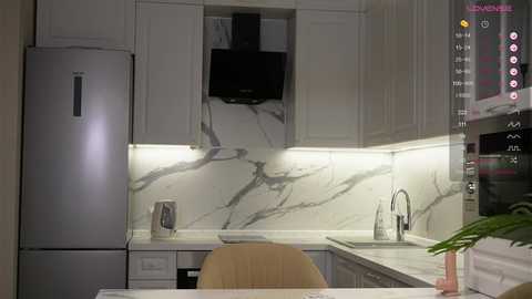 A modern kitchen with white cabinets, marble countertops, stainless steel appliances, and a wooden chair; ambient lighting highlights the sleek, clean design.