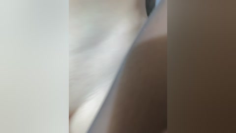 A close-up video of a nude, light-skinned woman's torso and breast, with blurred background, highlighting smooth skin texture and subtle shadows.