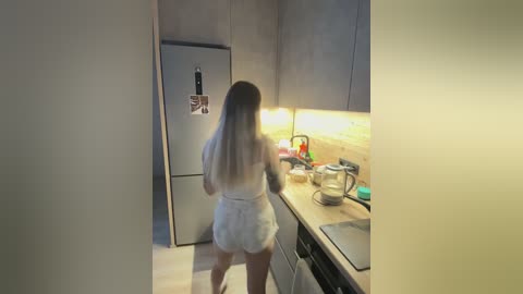 A video of a woman with long, blonde hair, wearing a white bathrobe, cooking in a modern, minimalist kitchen.
