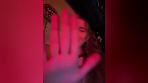 A video of a person with long hair, wearing a dark jacket, partially obscured by a red filter. The image is slightly blurred, creating a dreamy, surreal effect.