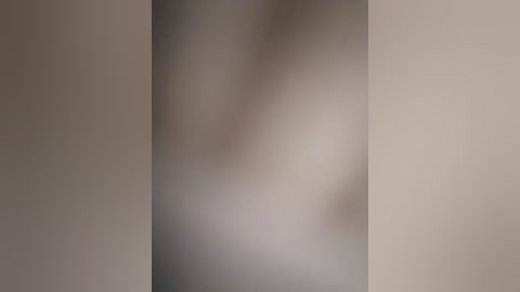 Blurry video of a nude person standing in a dimly lit room, with soft, muted colors dominating the background.