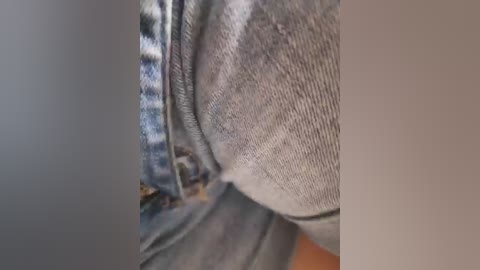 A close-up video of a person's waist, showing the seam of blue and white plaid shorts and a grey knit top. The image focuses on the fabric texture and stitching details.