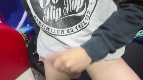 Video of a person in a grey hoodie with \"Go High\" text, lifting up their pants, revealing a partially erect penis. Background shows a red car and a blue object.