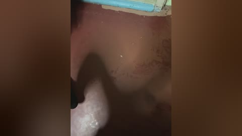 A close-up video of a human mouth with visible teeth, tongue, and saliva, partially obscured by a blue object. The background is dark and blurry.