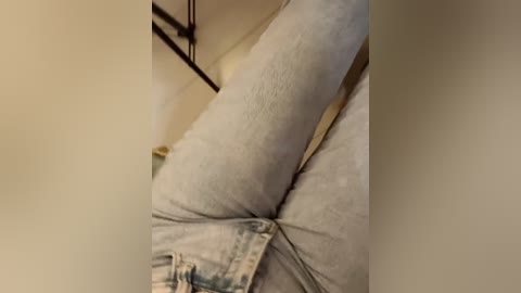 A close-up video of a person's legs in light blue jeans, showing a prominent butt crack and a glimpse of a beige fabric beneath.