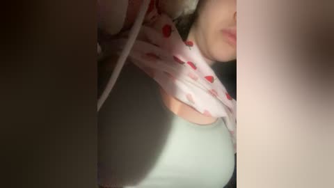 Video of a woman in a pink dress with strawberries, lying on her side. Her face is partially visible, with red lipstick and light skin. Background is blurred, focusing on her body.