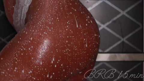 Video of a nude person with a dark brown complexion, covered in water droplets, standing in a tiled shower with a diamond-patterned backdrop.
