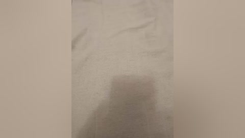 A video of a beige wall with a faint, rectangular shadow, possibly from a person or object, casting a slight distortion on the surface.