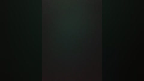 A dark, blurry video with a vertical band of light, possibly indicating a window or light source, set against a deep green background, creating a mysterious and slightly ominous atmosphere.