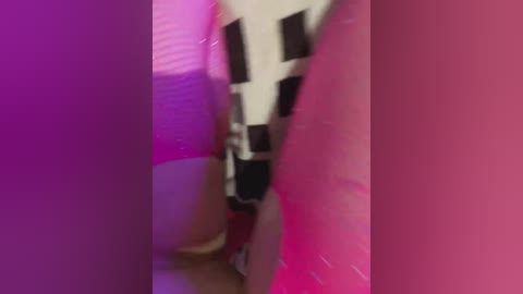 Video of a white robot with black eyes and a metallic texture, partially obscured by a pinkish background. The image is slightly blurred, making it difficult to discern details.