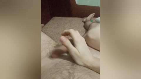 Video of a nude male with a circumcised penis, lying on a brown couch. The background includes a green wall and a brown armchair.