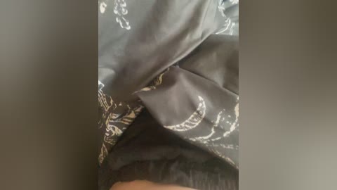 A video showing a close-up of a person's face partially covered by dark grey fabric with white floral patterns. The fabric appears to be draped over the person's head, obscuring most of their face except for their mouth and chin.