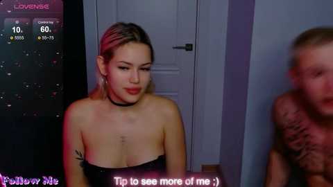 Video of a young woman with light skin, dark hair, and black choker, wearing a strapless top, in a dimly-lit room, partially blurred, with a caption reading \"To be seen more of me.\
