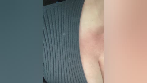 Video of a person's upper torso, showing a portion of their chest with a noticeable red mark on the left side, partially covered by a ribbed, dark grey tank top.