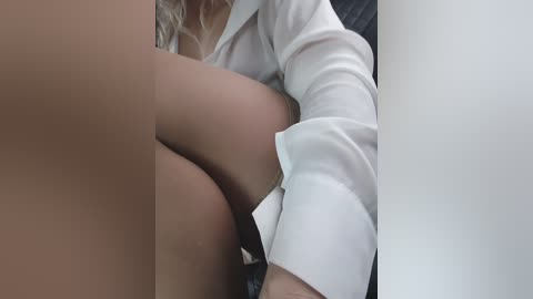 Video of a woman in a white blouse, her legs wrapped around another person's, possibly a man, suggesting a sensual or intimate scenario.