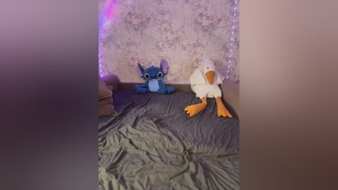 Video of a cozy bedroom with a gray bedspread, a stuffed Stitch and Donald Duck toy, and a floral-patterned wall with fairy lights.