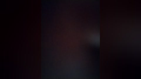 This is a dimly lit video with a blurred, indistinct subject in the center, surrounded by dark, moody hues of red and black, creating a mysterious and slightly ominous atmosphere.