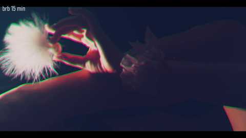 A dimly lit, grainy video showing a person with a fuzzy, white, feathery texture on their hand, illuminated by a bright light. The background is dark, suggesting a nighttime setting.