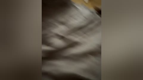 A blurred video of a person with light skin, possibly a woman, lying on a bed with white sheets, partially visible, and a yellow pillow in the background.