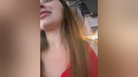 A blurred video of a woman with long brown hair, fair skin, and wearing a red top, captured from a low angle.