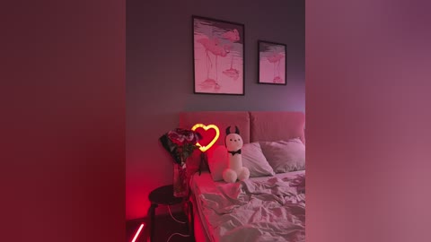 Video of a modern bedroom with a plush white cat toy on a bed, a neon heart light on a side table, and a pink floral painting on the wall.