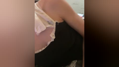 Video of a woman in a revealing black and white lace French maid outfit, with visible cleavage, leaning against a beige wall in a dimly lit room.