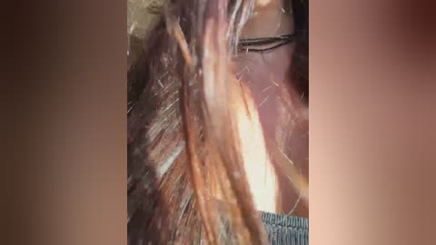 A close-up video of a person with shoulder-length, messy brown hair, showing strands tangled and wet. The background is blurred, with a muted brown color. The image captures a candid, unstyled look.