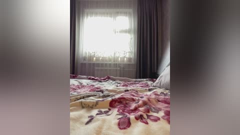 A video of a cozy bedroom with a floral-patterned blanket on the bed, sheer curtains, and a window with a view of a garden. The room is softly lit, creating a warm, inviting atmosphere.
