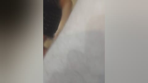 A close-up video of a human eye, partially obscured by a white, blurry object, likely a bandage or tissue, covering the pupil. The iris is visible, with a blend of brown and green hues. The image is grainy, suggesting it might be taken with a low-quality camera or under poor lighting conditions.