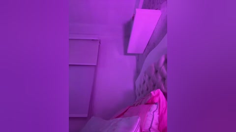 Video of a dimly lit, purple-lit bedroom with a person's arm reaching out of the frame, partially visible under a blanket. A window with a white blind is on the left, and a pink sheet is on the bed.